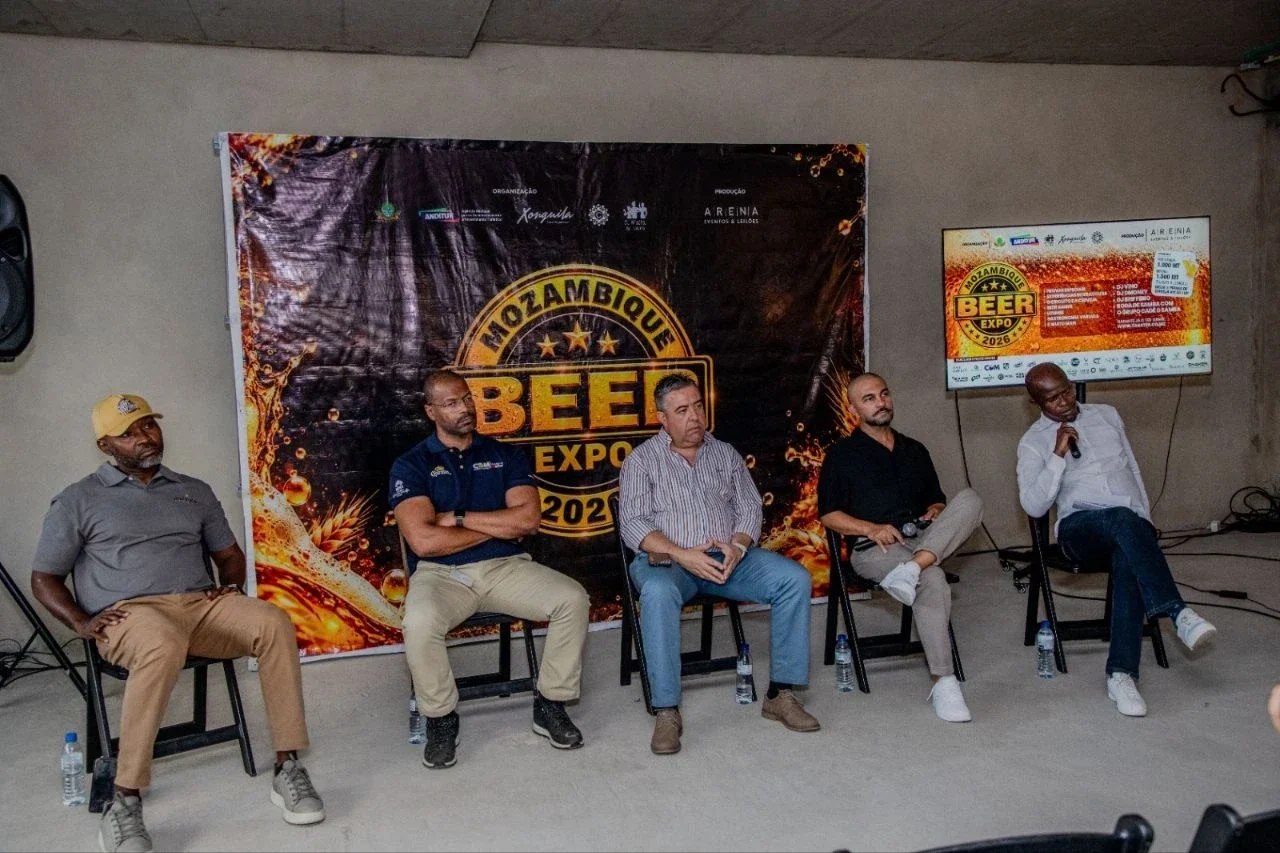 Cinco oradores sentados num painel, em frente ao cartaz da Mozambique Beer Expo 2026.